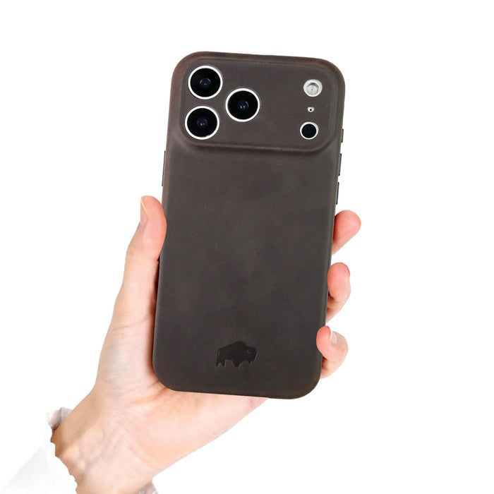 A hand holds the BlackBrook Case Ryker Leather iPhone 17 Pro Max MagSafe Case in distressed coffee, featuring a buffalo logo.